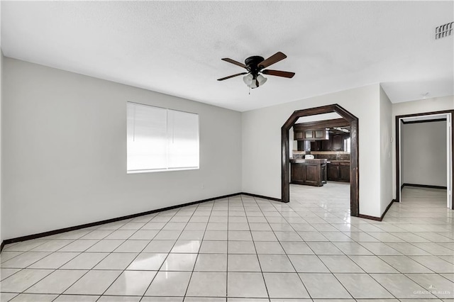 tiled empty room featuring ceiling fan and a textured ceiling