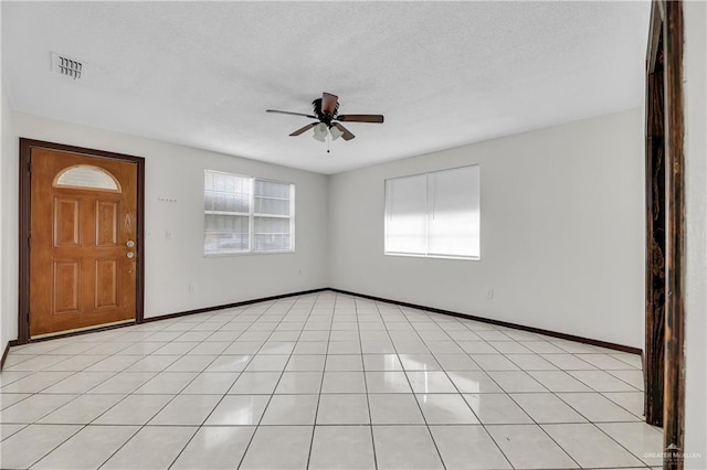 foyer entrance with ceiling fan, a healthy amount of sunlight, and light tile patterned floors