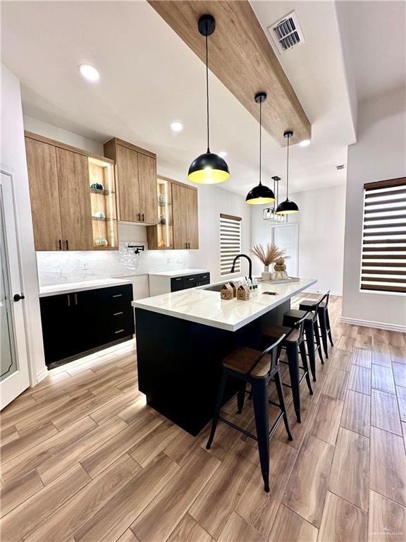 kitchen featuring a center island with sink, sink, a breakfast bar area, and pendant lighting