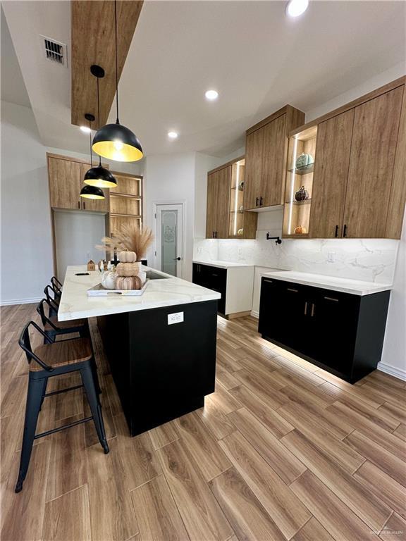 kitchen with decorative backsplash, a breakfast bar, and hanging light fixtures