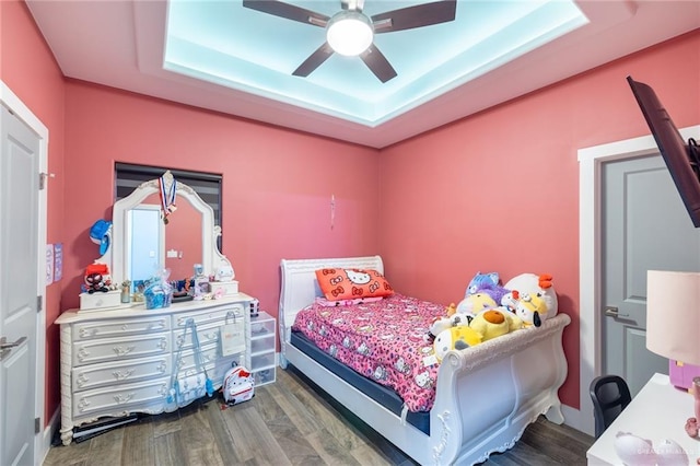 bedroom with a tray ceiling, dark wood finished floors, and a ceiling fan