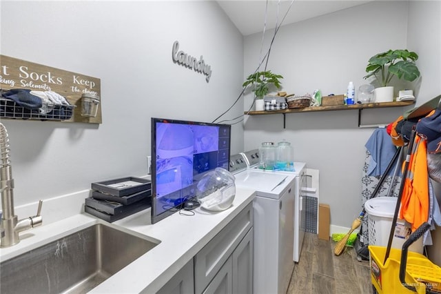 laundry room featuring a sink, cabinet space, washing machine and dryer, and dark wood-type flooring