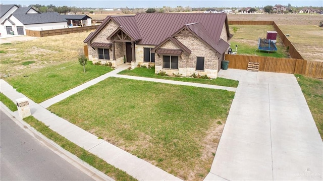 view of front of property featuring stone siding, metal roof, a standing seam roof, fence, and a front lawn