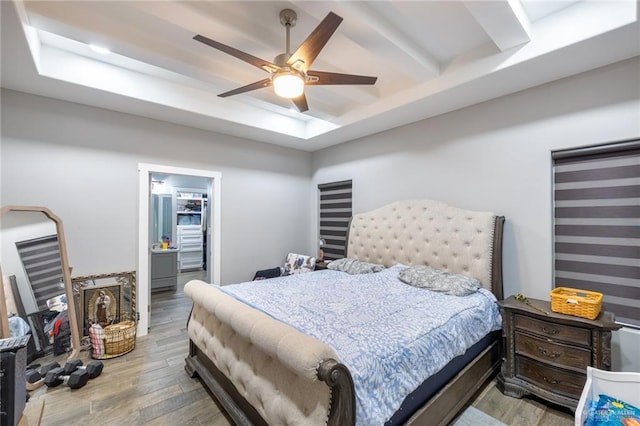 bedroom featuring a tray ceiling, light wood-style flooring, and a ceiling fan