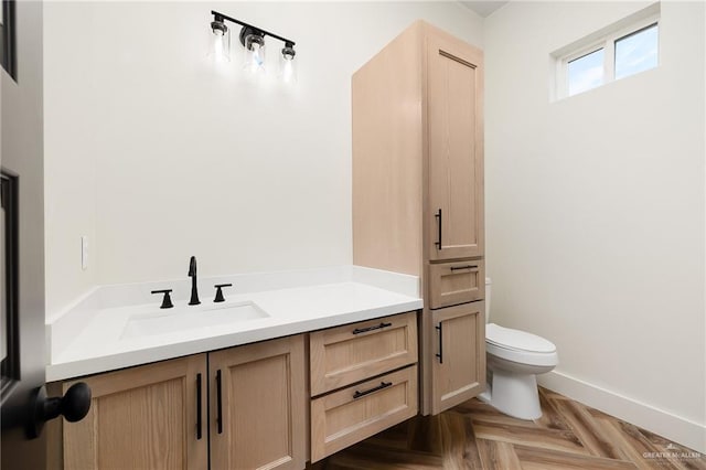 bathroom with toilet, parquet floors, and vanity