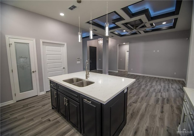 kitchen featuring light countertops, visible vents, a sink, wood finished floors, and dark cabinets