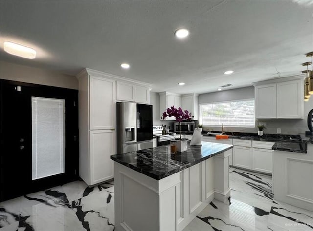 kitchen with appliances with stainless steel finishes, white cabinetry, and pendant lighting