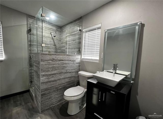 bathroom with hardwood / wood-style flooring, a shower with door, vanity, and toilet