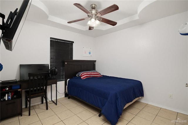 bedroom with ceiling fan, light tile patterned floors, and a tray ceiling