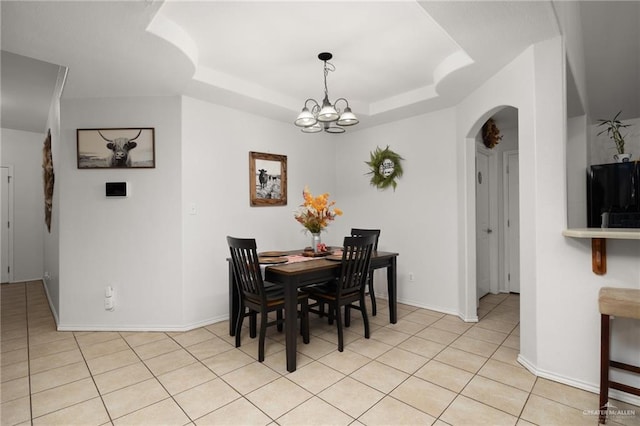 dining area featuring a raised ceiling, a notable chandelier, and light tile patterned flooring