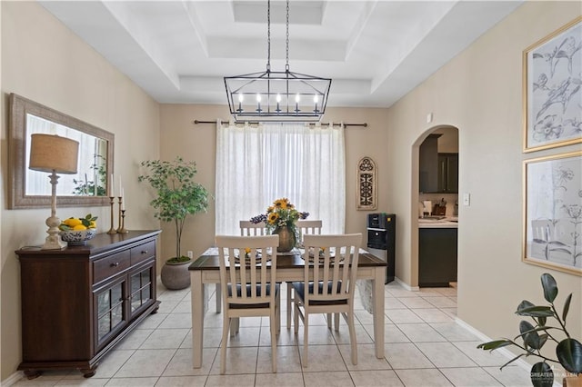1602 Meadow Ln, Harlingen, TX 78550 - dining room featuring a tray ceiling, arched walkways, a chandelier, and light tile patterned floors