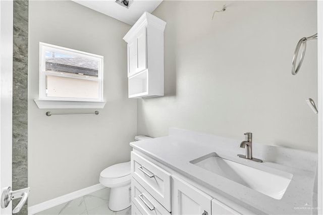 bathroom featuring marble finish flooring, toilet, vanity, and baseboards