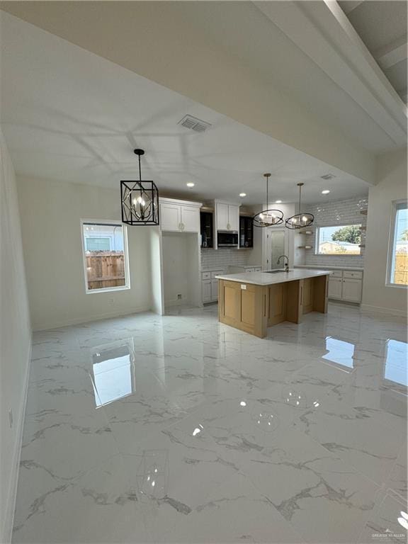 805 E Costa Del Sol Ave, Edinburg, TX 78542 - kitchen with stainless steel microwave, visible vents, an inviting chandelier, backsplash, and baseboards