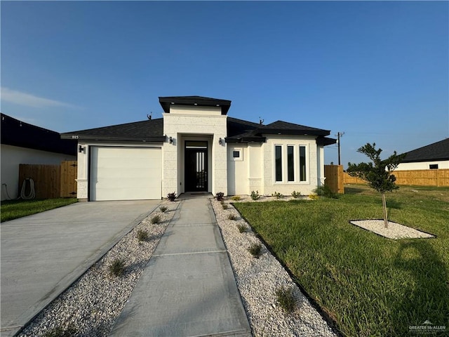 805 E Costa Del Sol Ave, Edinburg, TX 78542 - prairie-style house featuring an attached garage, fence, driveway, a front lawn, and roof with shingles