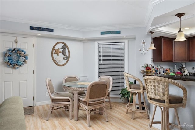 dining space featuring light hardwood / wood-style floors, crown molding, and sink