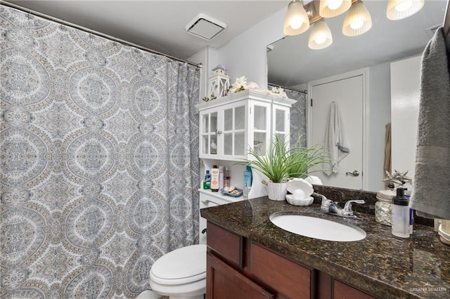 bathroom featuring vanity, toilet, and an inviting chandelier