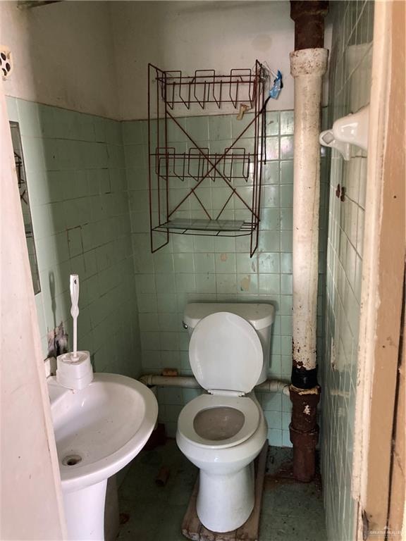 bathroom with toilet, tile walls, and sink