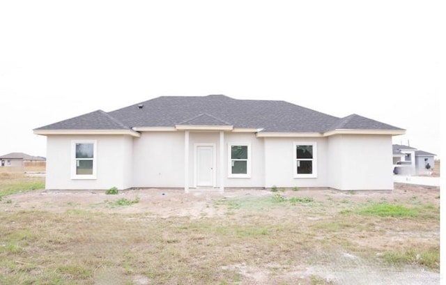 rear view of house featuring stucco siding and roof with shingles