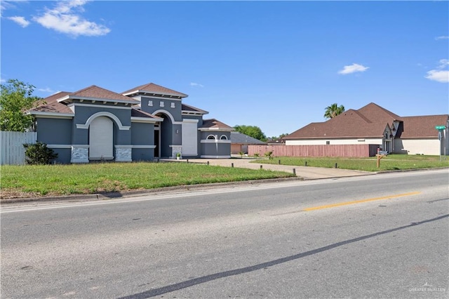 view of front of house with stucco siding, fence, and a front yard