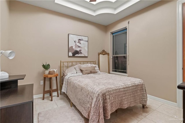 bedroom featuring light tile patterned floors, baseboards, and a raised ceiling
