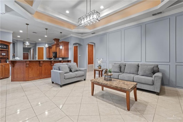 living area with a decorative wall, visible vents, ornamental molding, and arched walkways