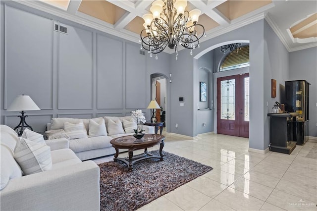 living room featuring a decorative wall, ornamental molding, arched walkways, and a chandelier