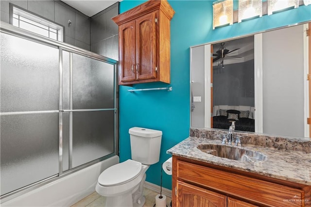 bathroom featuring combined bath / shower with glass door, vanity, toilet, and ceiling fan