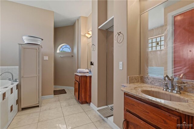 full bath featuring tile patterned floors, tiled tub, vanity, and baseboards