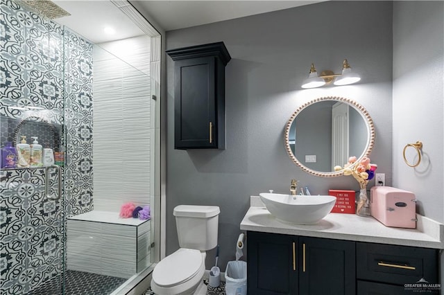 bathroom with vanity, toilet, and tiled shower