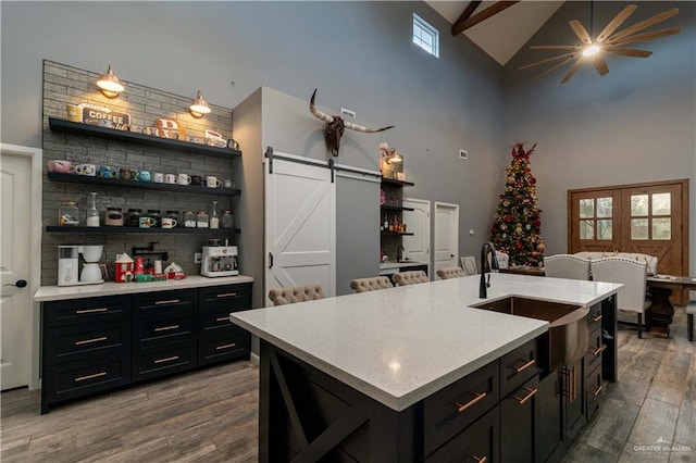 kitchen with hardwood / wood-style floors, a barn door, plenty of natural light, and an island with sink