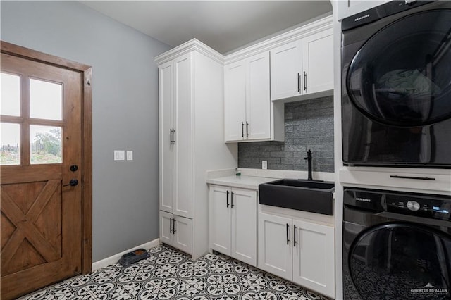 laundry room with cabinets, light tile patterned flooring, stacked washer / dryer, and sink