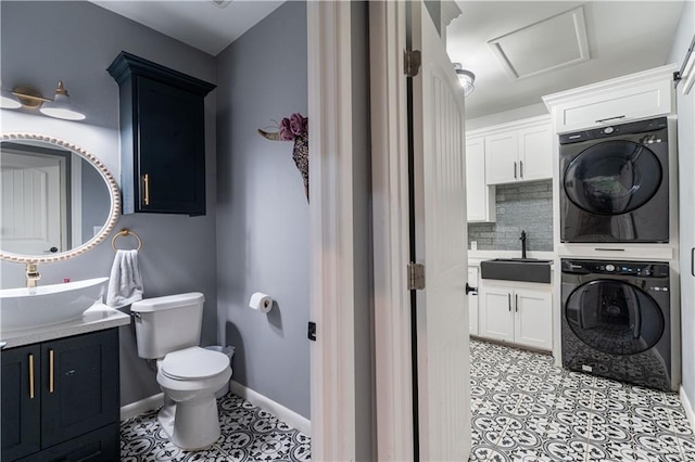 bathroom featuring tasteful backsplash, tile patterned floors, vanity, toilet, and stacked washer / drying machine