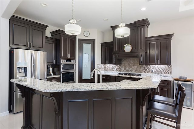 kitchen featuring a breakfast bar, decorative light fixtures, backsplash, and appliances with stainless steel finishes