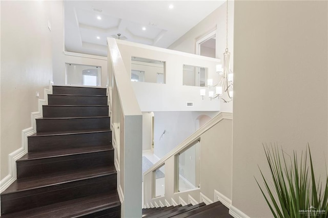 staircase with a high ceiling and a notable chandelier