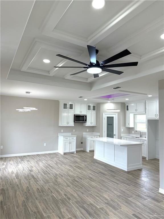 kitchen with a kitchen island, ceiling fan, light hardwood / wood-style flooring, white cabinetry, and hanging light fixtures