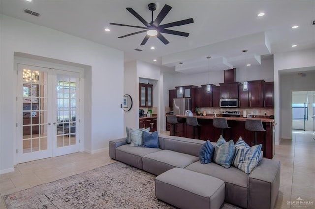 living room with french doors, ceiling fan with notable chandelier, and light tile patterned floors