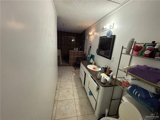 bathroom with tile patterned flooring, a tile shower, vanity, and ornamental molding