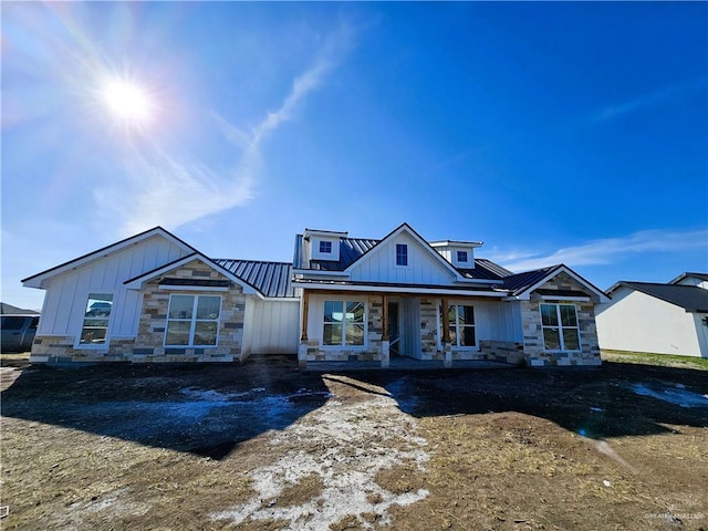 view of front of property featuring stone siding, metal roof, board and batten siding, and a standing seam roof