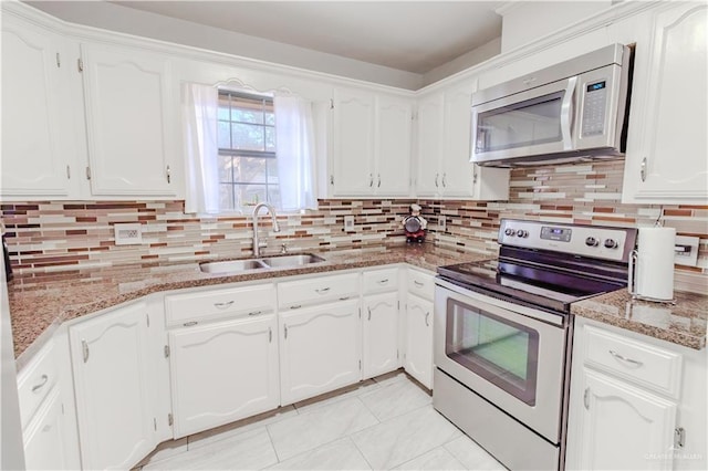 kitchen with appliances with stainless steel finishes, a sink, white cabinetry, and decorative backsplash