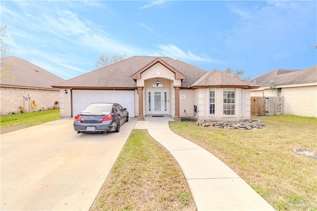 view of front of home featuring concrete driveway, roof with shingles, an attached garage, and a front yard