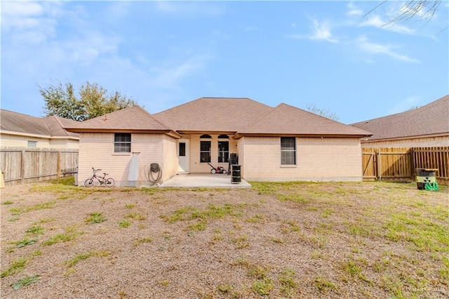 back of property featuring a patio area, a fenced backyard, a lawn, and brick siding