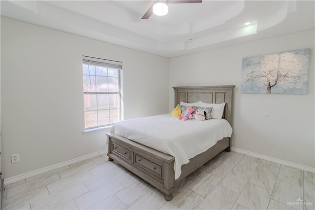 bedroom featuring ceiling fan, a raised ceiling, and baseboards