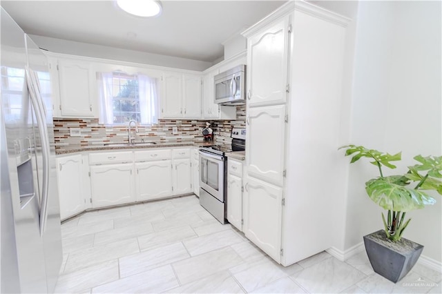 kitchen featuring appliances with stainless steel finishes, white cabinets, a sink, and decorative backsplash