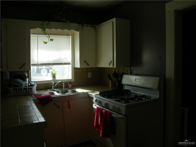 501 W Lovett St, Edinburg, TX 78541 - kitchen with tasteful backsplash, a sink, tile countertops, white gas range oven, and white cabinetry