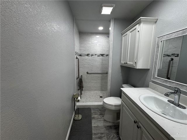 bathroom with tiled shower, vanity, and toilet