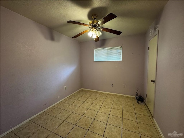 spare room with ceiling fan, light tile patterned flooring, and a textured ceiling