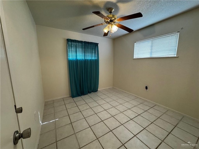 tiled empty room with ceiling fan and a textured ceiling