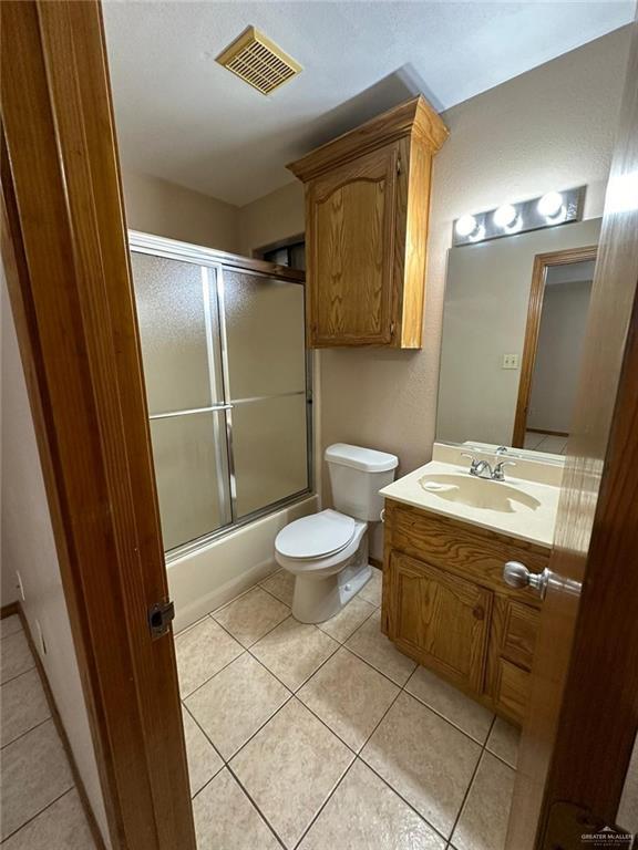 full bathroom featuring tile patterned flooring, vanity, toilet, and combined bath / shower with glass door