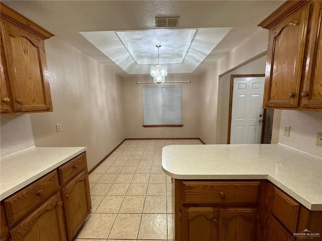 kitchen with kitchen peninsula, a raised ceiling, light tile patterned floors, an inviting chandelier, and hanging light fixtures