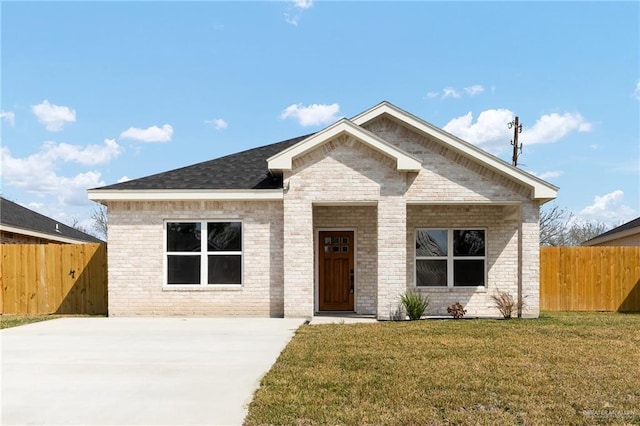 view of front of house featuring fence, brick siding, and a front yard